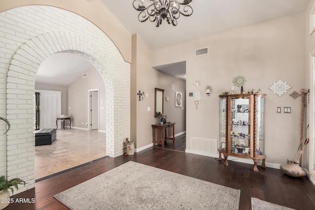 entryway featuring an inviting chandelier, dark hardwood / wood-style flooring, and high vaulted ceiling