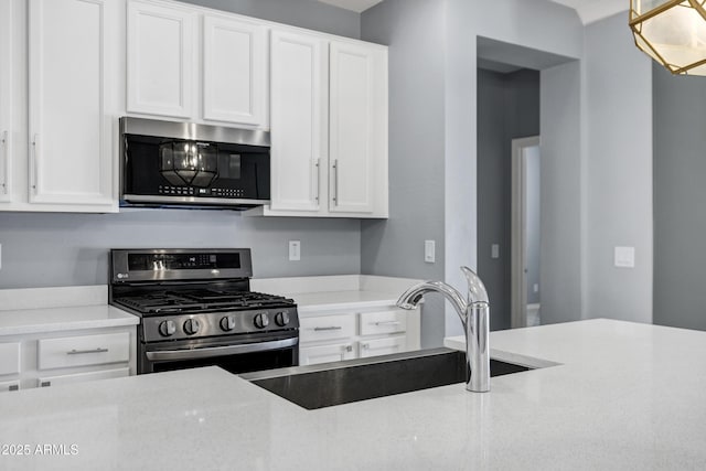 1272 W Joshua Tree Ave, Queen Creek, AZ 85140 - kitchen with appliances with stainless steel finishes, a sink, white cabinets, and hanging light fixtures