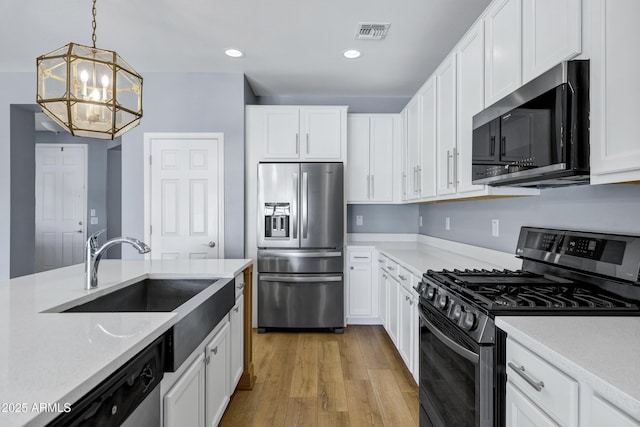 1272 W Joshua Tree Ave, Queen Creek, AZ 85140 - kitchen featuring appliances with stainless steel finishes, a chandelier, white cabinets, a sink, and light wood-style flooring