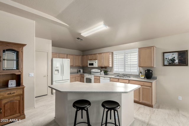 kitchen with sink, white appliances, a breakfast bar, a center island, and light brown cabinetry