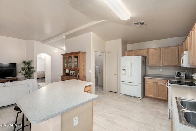 kitchen featuring a breakfast bar, a center island, vaulted ceiling, light brown cabinets, and white appliances