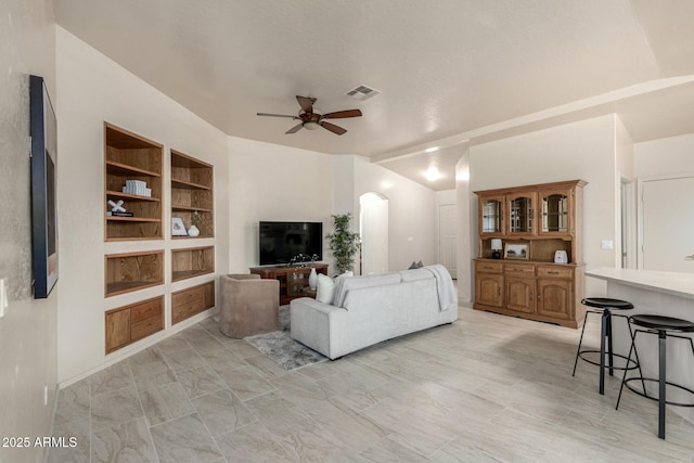 living room featuring built in features and ceiling fan