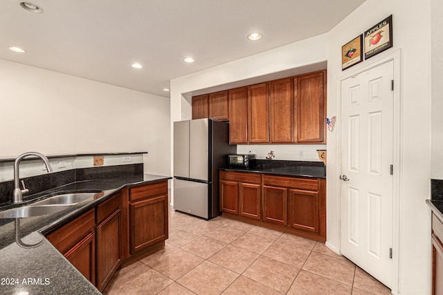 kitchen with light tile patterned flooring, stainless steel fridge, and sink