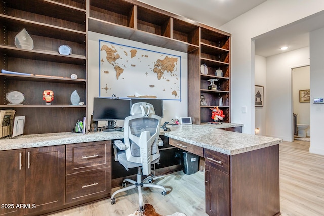 home office featuring light wood-type flooring, built in study area, and baseboards