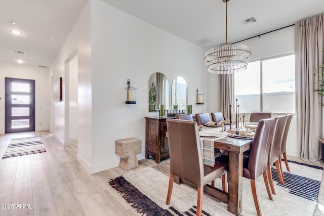 dining space with a healthy amount of sunlight, visible vents, a notable chandelier, and light wood finished floors