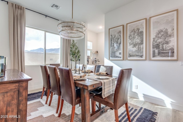 dining space with a chandelier, a mountain view, visible vents, baseboards, and light wood-type flooring