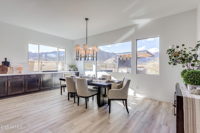 dining space featuring baseboards, a notable chandelier, a mountain view, and light wood finished floors