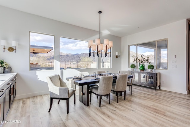 dining space featuring light wood-style floors, baseboards, a mountain view, and a chandelier