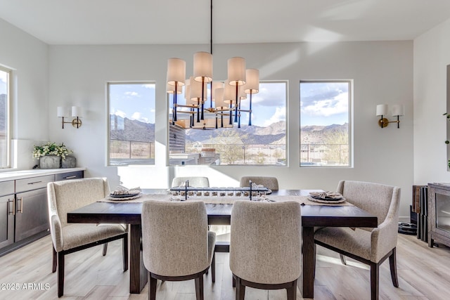 dining room with a mountain view, light wood finished floors, and an inviting chandelier