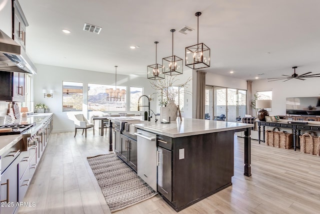 kitchen featuring dishwasher, an island with sink, open floor plan, light countertops, and pendant lighting