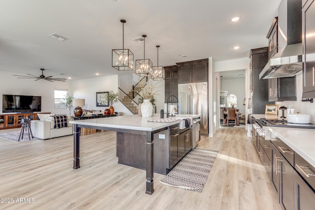 kitchen featuring a breakfast bar, pendant lighting, a center island with sink, island exhaust hood, and open floor plan