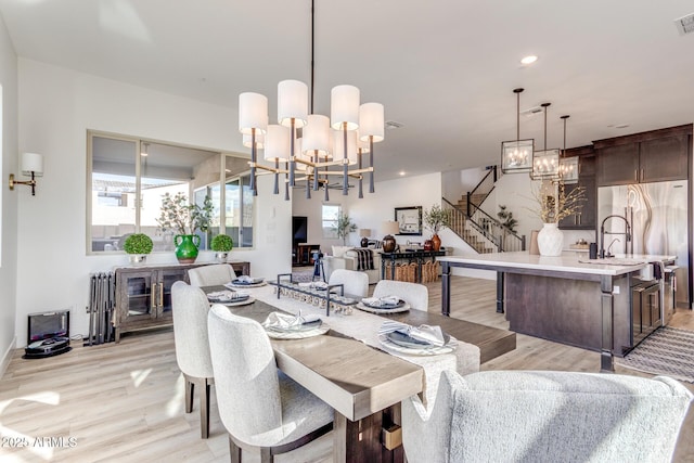 dining area with recessed lighting, a notable chandelier, visible vents, stairs, and light wood finished floors