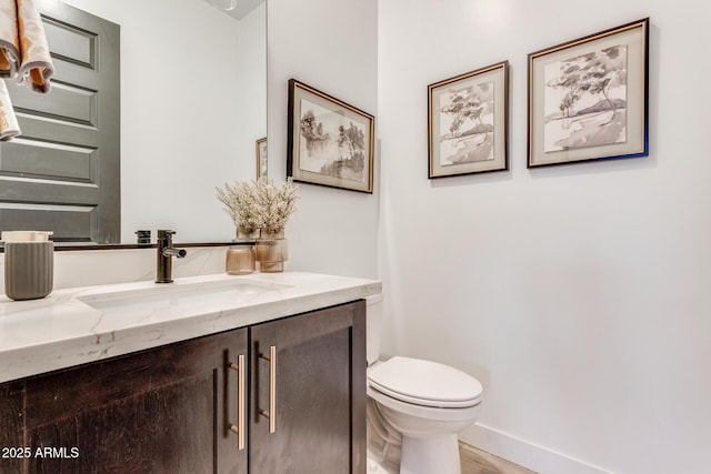 bathroom featuring toilet, wood finished floors, vanity, and baseboards