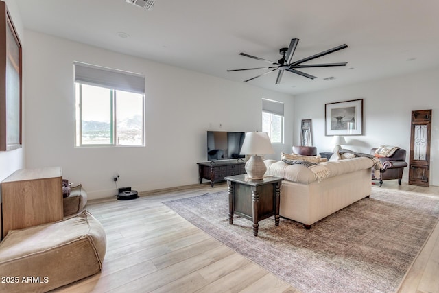 living area featuring light wood finished floors, ceiling fan, and visible vents