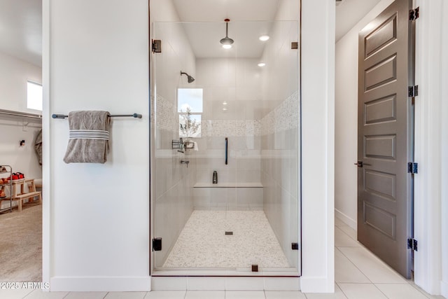 bathroom with a stall shower, a spacious closet, baseboards, and tile patterned floors