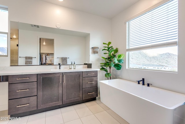 bathroom featuring a soaking tub, tile patterned floors, visible vents, and vanity