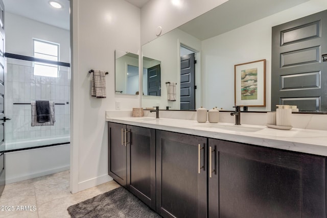 full bathroom featuring double vanity, enclosed tub / shower combo, a sink, and tile patterned floors