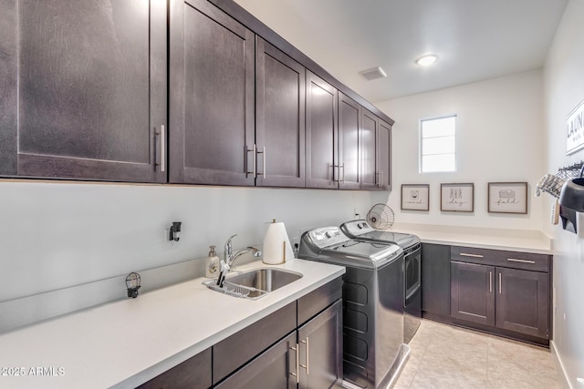 laundry area with light tile patterned floors, washing machine and dryer, a sink, visible vents, and cabinet space