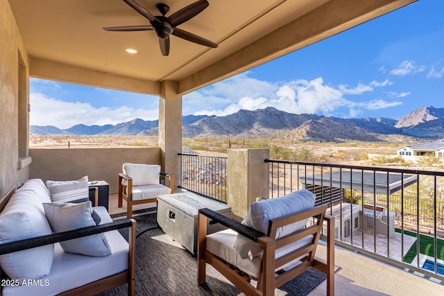 view of patio / terrace featuring a ceiling fan, an outdoor living space with a fire pit, a mountain view, and a balcony