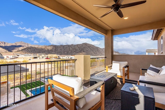 view of patio / terrace with a ceiling fan, an outdoor living space with a fire pit, a mountain view, and a balcony