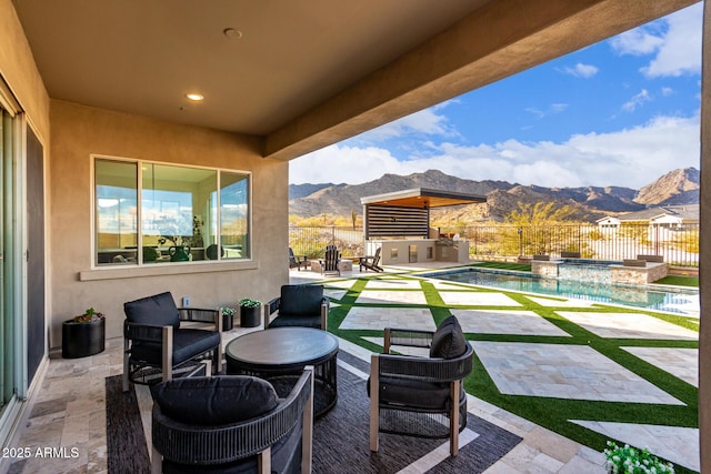 view of patio with a fenced in pool, an outdoor kitchen, a mountain view, an in ground hot tub, and a fenced backyard