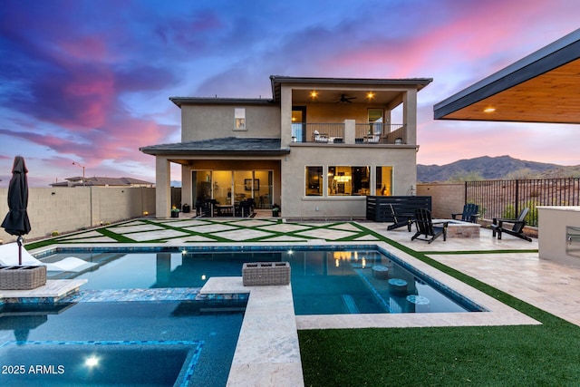 back of property featuring an outdoor fire pit, a balcony, a mountain view, a fenced in pool, and stucco siding