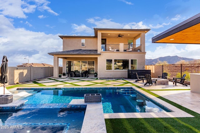 rear view of property featuring a ceiling fan, an outdoor fire pit, a patio area, a mountain view, and a balcony