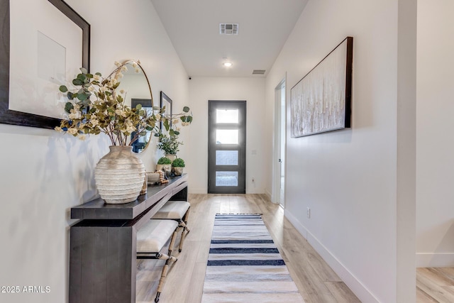 doorway featuring visible vents, light wood-style flooring, and baseboards