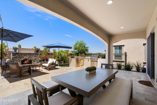 view of patio featuring a grill, fence, an outdoor kitchen, an outdoor living space with a fireplace, and outdoor dining area