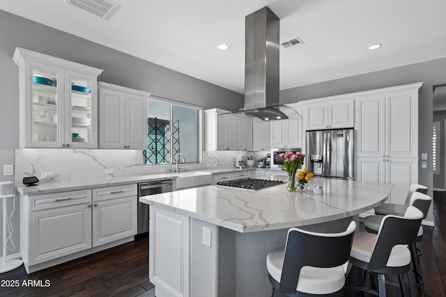 kitchen featuring island range hood, appliances with stainless steel finishes, dark wood-style flooring, visible vents, and a kitchen island