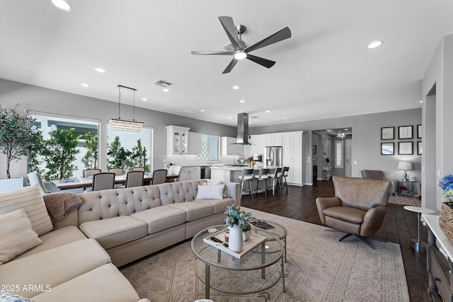 living room featuring dark wood finished floors, a healthy amount of sunlight, a ceiling fan, and visible vents