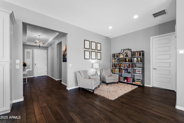 sitting room with an inviting chandelier, hardwood / wood-style floors, visible vents, and baseboards
