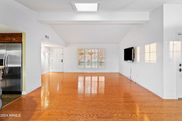 unfurnished living room with vaulted ceiling with beams and light hardwood / wood-style flooring