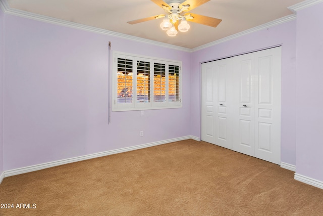 unfurnished bedroom featuring ceiling fan, a closet, light colored carpet, and ornamental molding