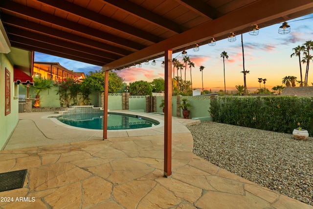 pool at dusk featuring a patio area