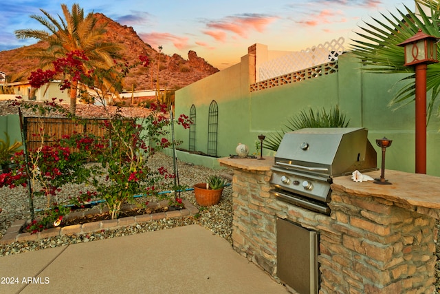 patio terrace at dusk with a mountain view, area for grilling, and a grill