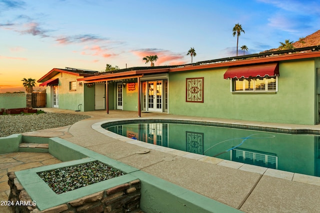 pool at dusk featuring a patio