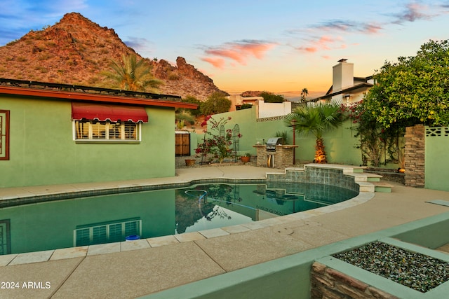 pool at dusk with a mountain view and area for grilling