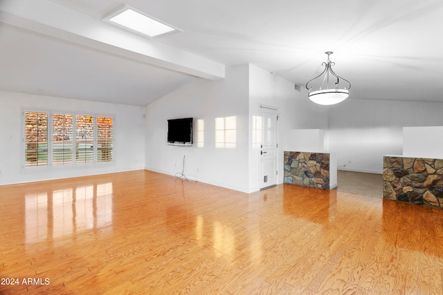 unfurnished living room with vaulted ceiling with beams and light wood-type flooring