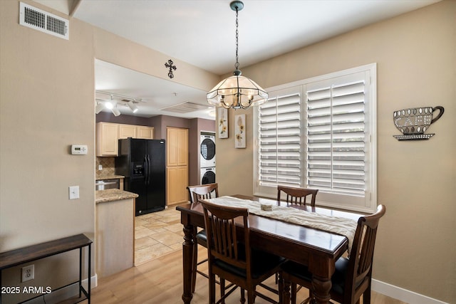 15151 N Frank Lloyd Wright Blvd Unit 2086, Scottsdale, AZ 85260 - dining room with stacked washer / drying machine, a chandelier, rail lighting, and light wood-style floors