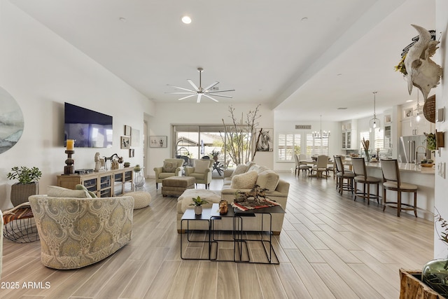 living room with ceiling fan with notable chandelier