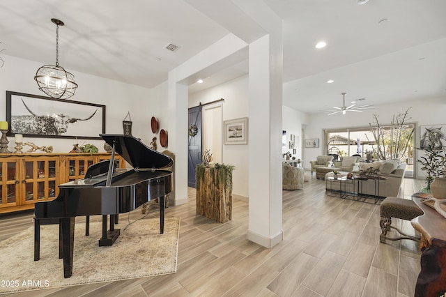 miscellaneous room with a barn door and ceiling fan with notable chandelier