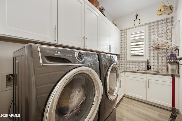 clothes washing area featuring cabinets, sink, and washing machine and clothes dryer