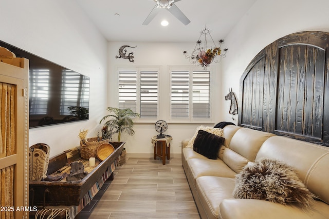 living room featuring ceiling fan with notable chandelier and light hardwood / wood-style flooring