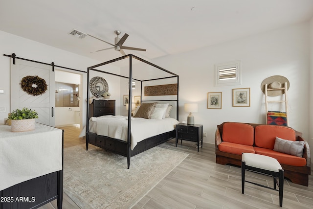 bedroom featuring ceiling fan and a barn door