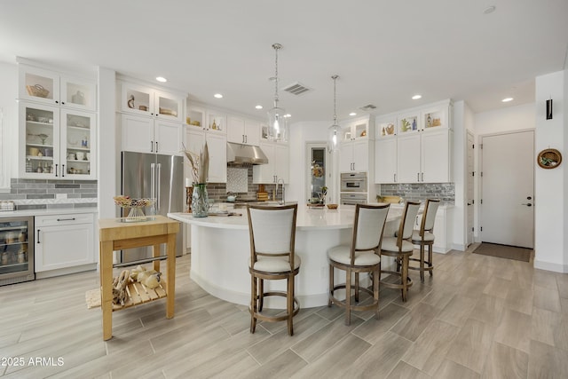 kitchen featuring wine cooler, a kitchen island with sink, white cabinets, and stainless steel appliances