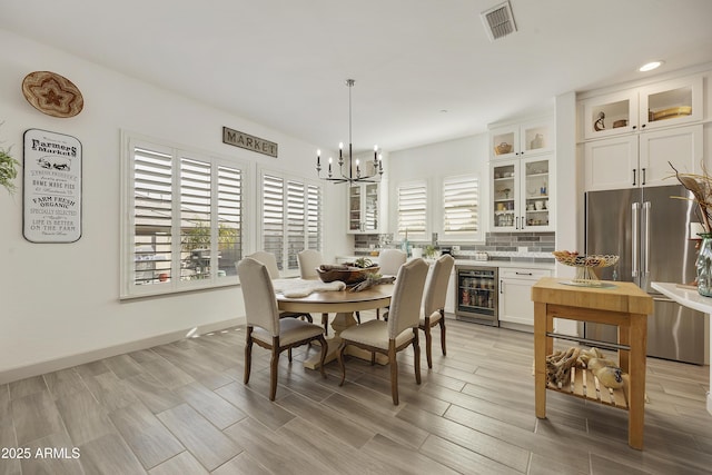 dining space featuring an inviting chandelier, plenty of natural light, and beverage cooler