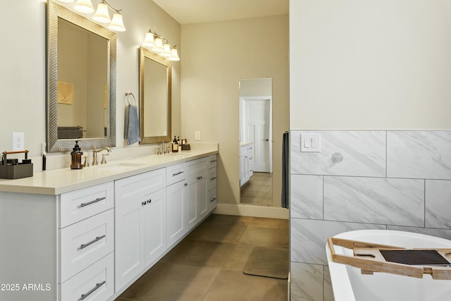 bathroom with double vanity, tile patterned flooring, a sink, and tile walls