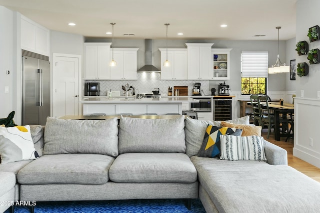 living room with wainscoting, wine cooler, light wood-type flooring, and recessed lighting