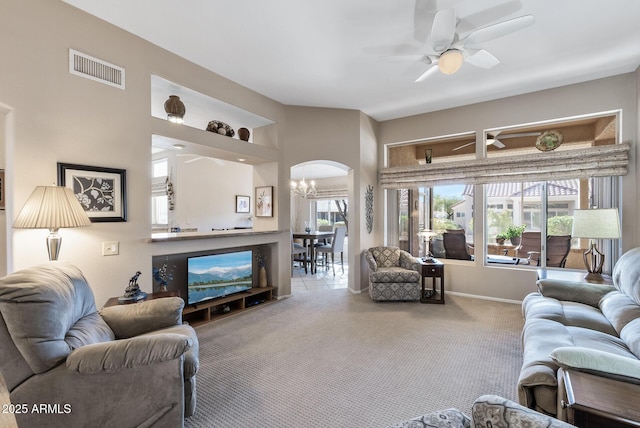 carpeted living room featuring ceiling fan with notable chandelier